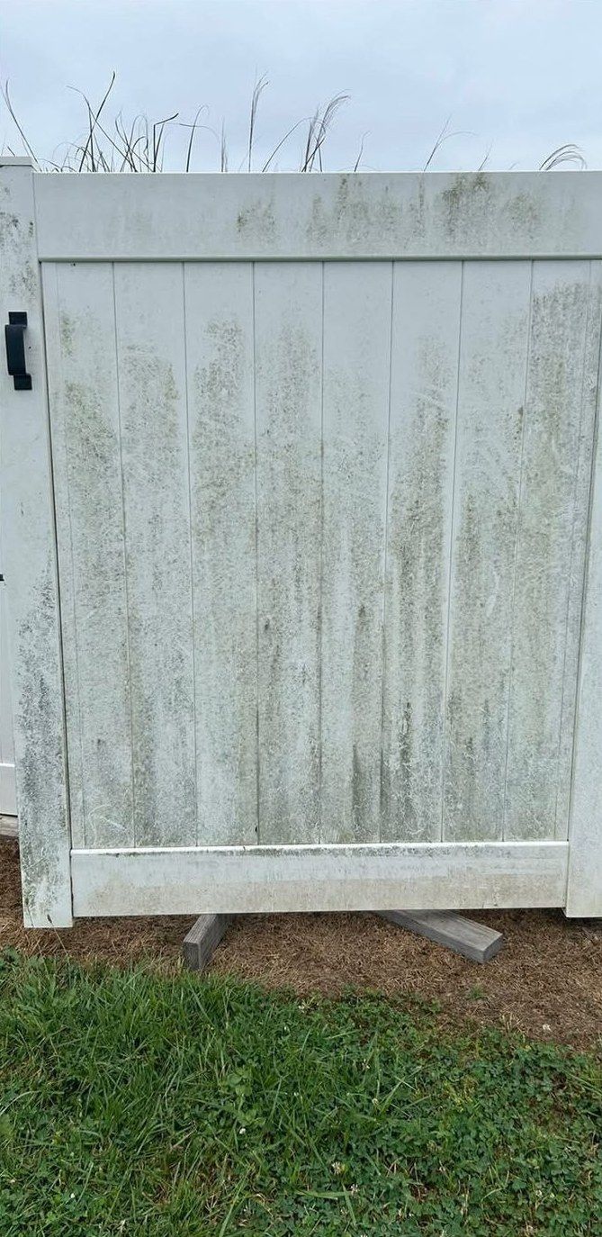 White vinyl fence gate streaked top to bottom with green mildew