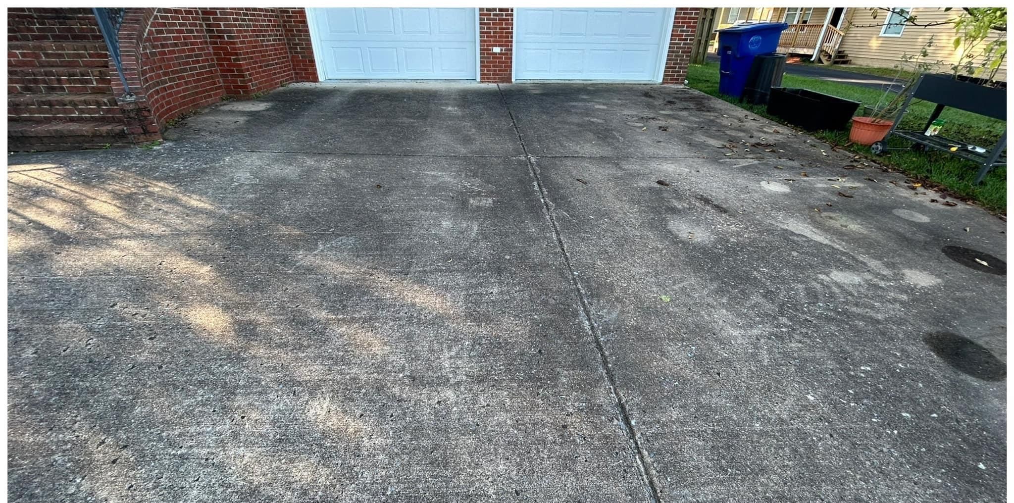 Two-car concrete driveway in front of a brick garage, gray with mildew and dark stains