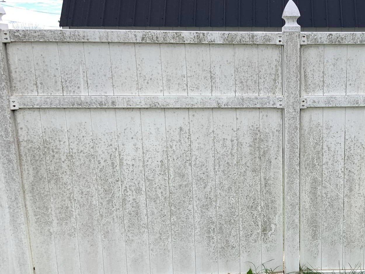 White vinyl privacy fence panel speckled with gray mildew
