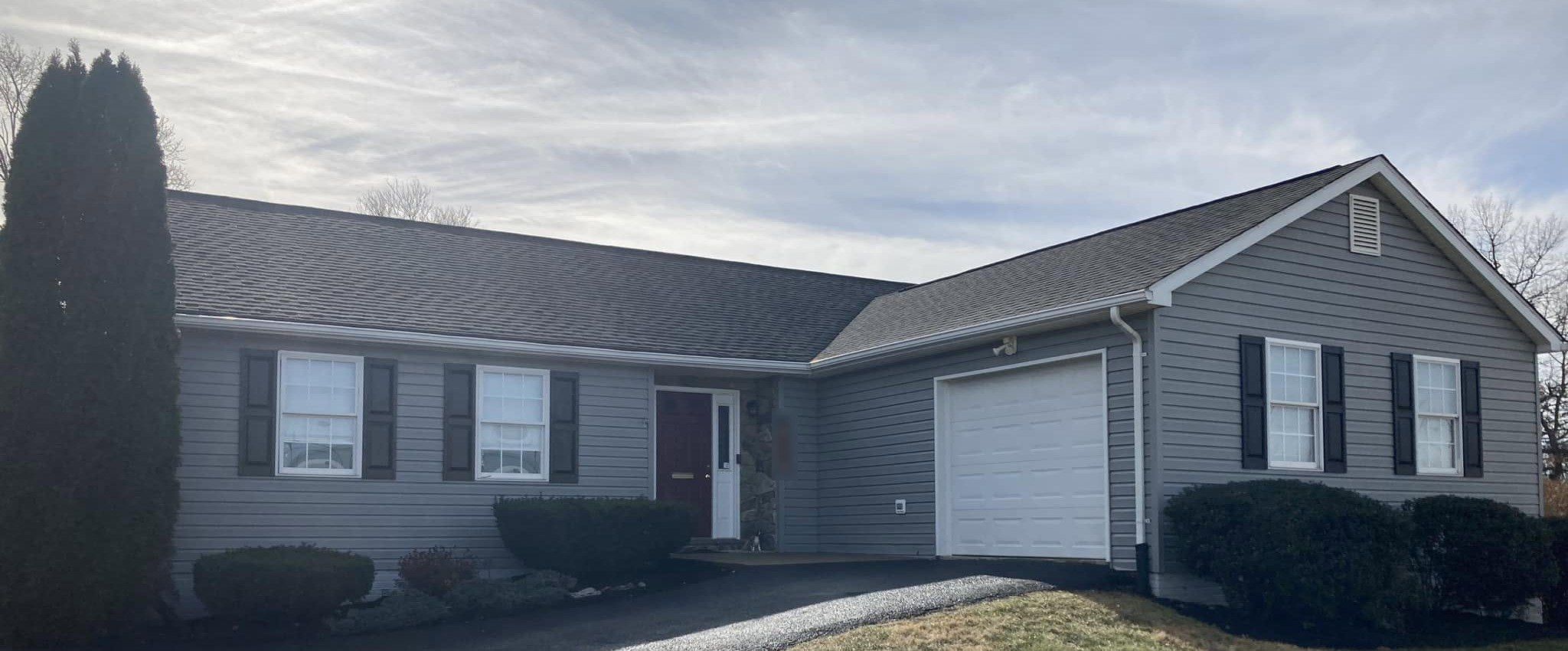 Gray vinyl ranch house with clean siding and roof on a sunny afternoon
