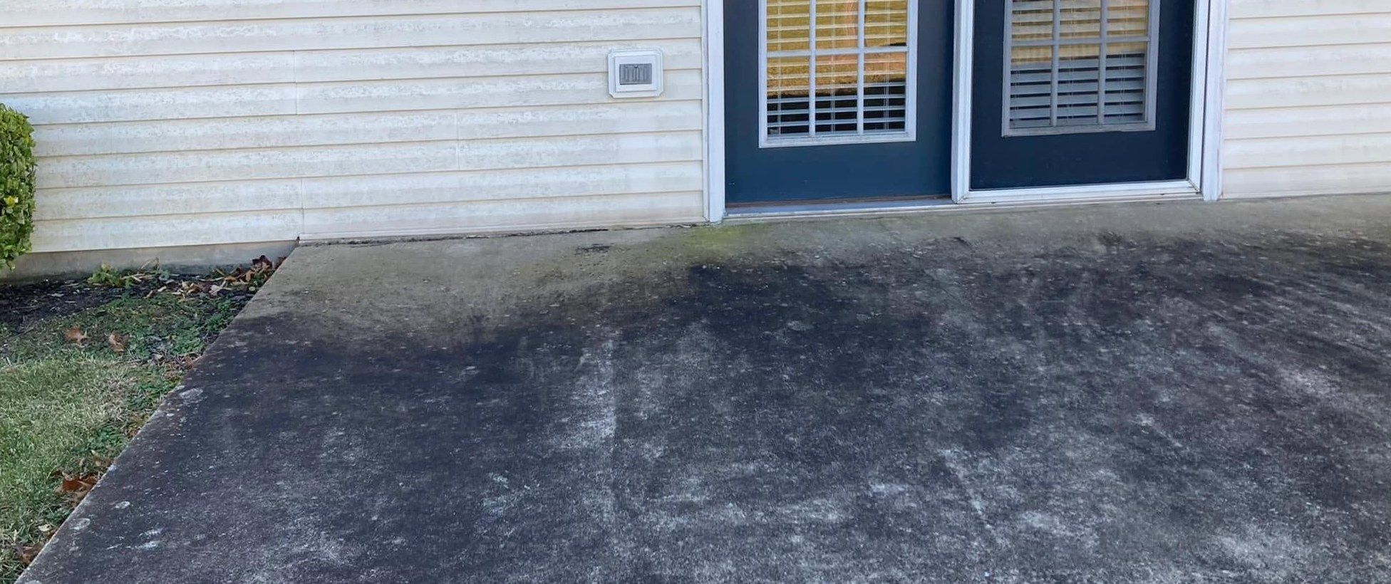 Concrete patio by blue doors, dark with black mildew and dirt