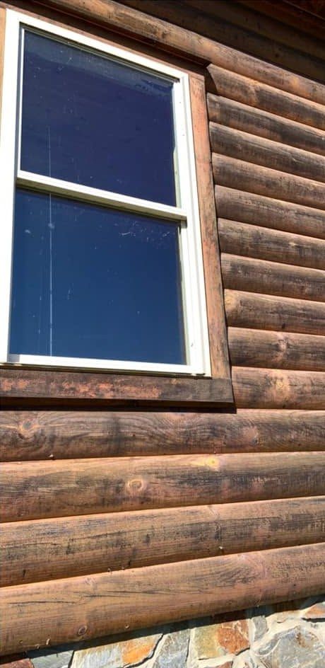 Dark weathered log siding around a window
