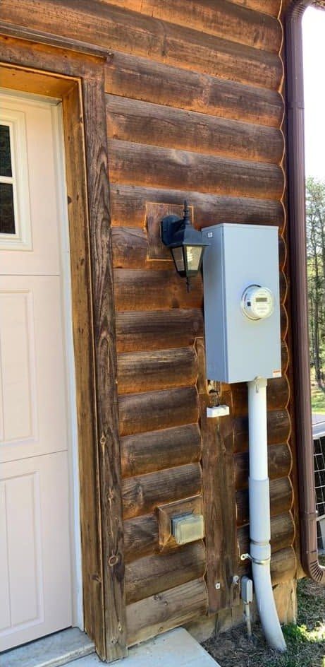 Dull gray log wall by a side door with a lantern and meter box