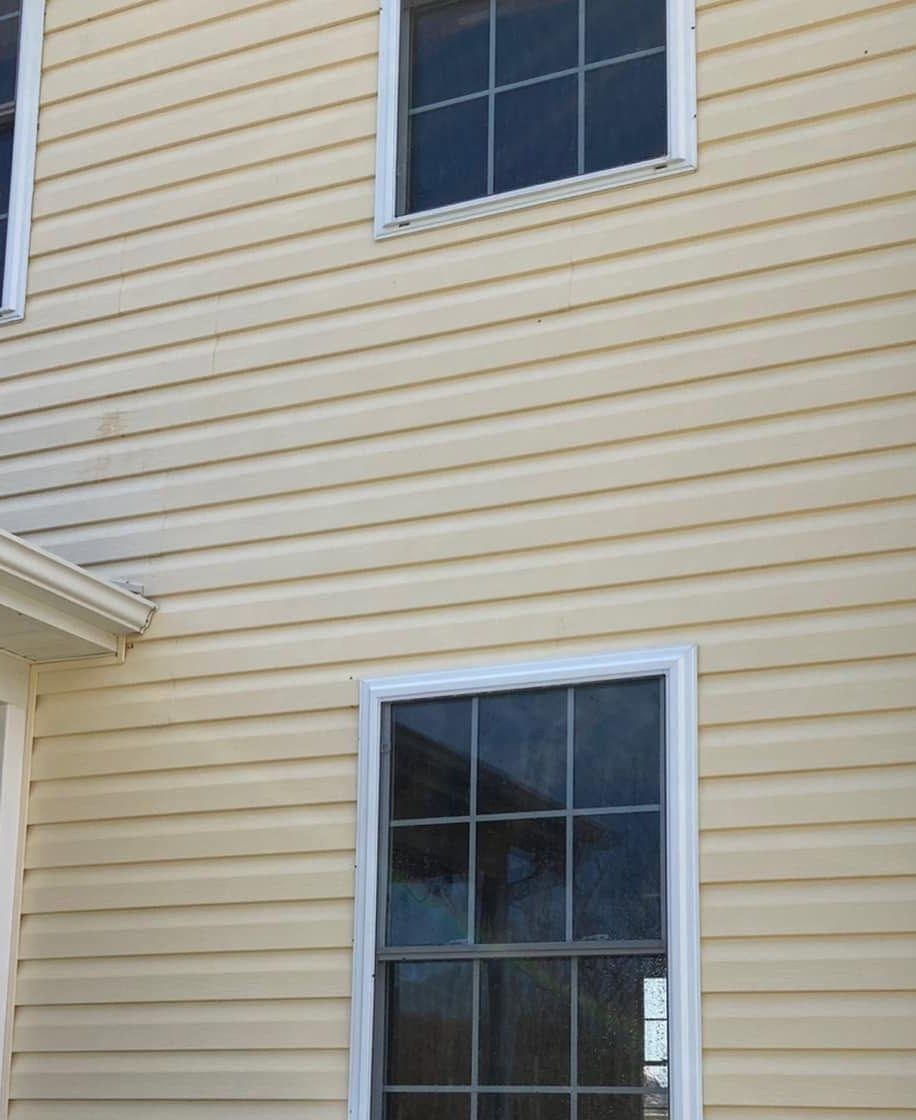 The same siding after washing, clean even yellow around both windows