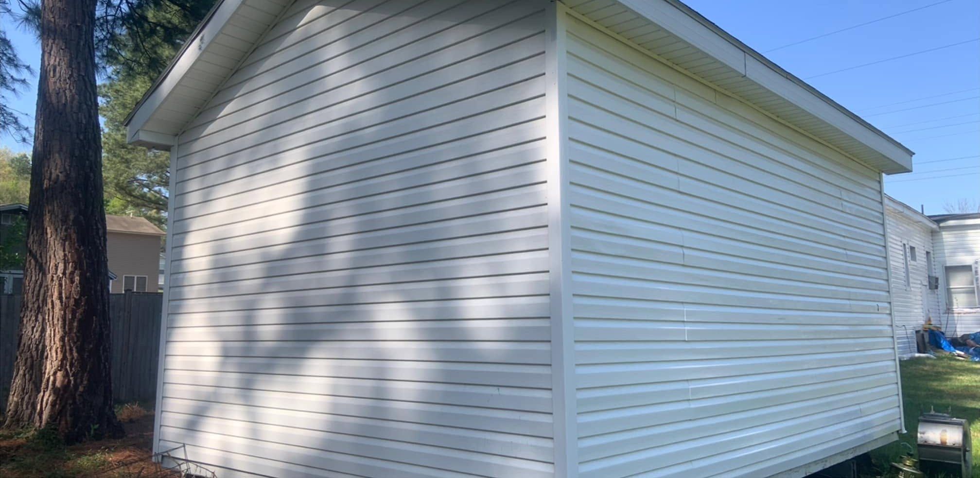 The same shed after washing, clean white siding on both walls