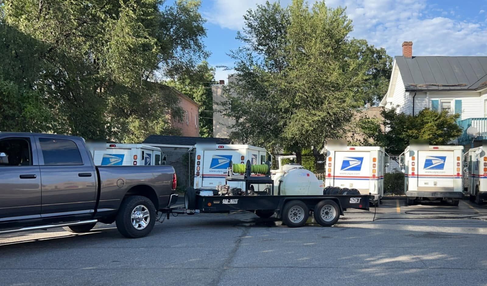 Our pickup and wash trailer parked beside a row of postal delivery trucks at the Woodstock post office