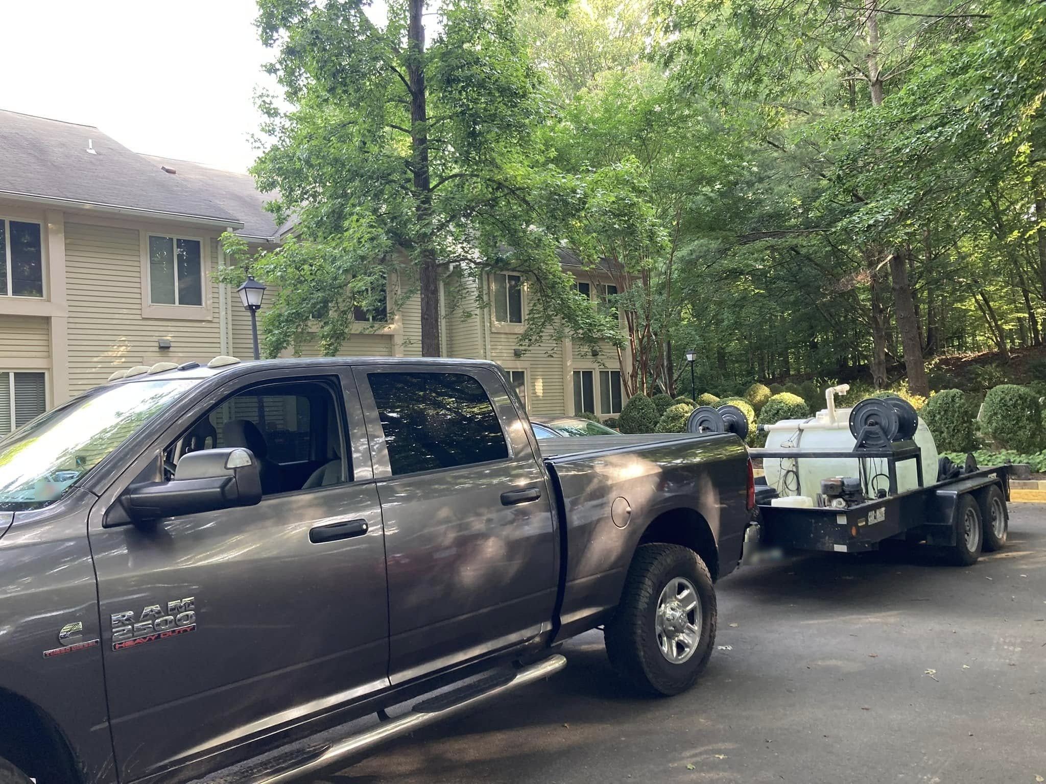 Crew-cab pickup towing an open trailer with a water tank and hose reels