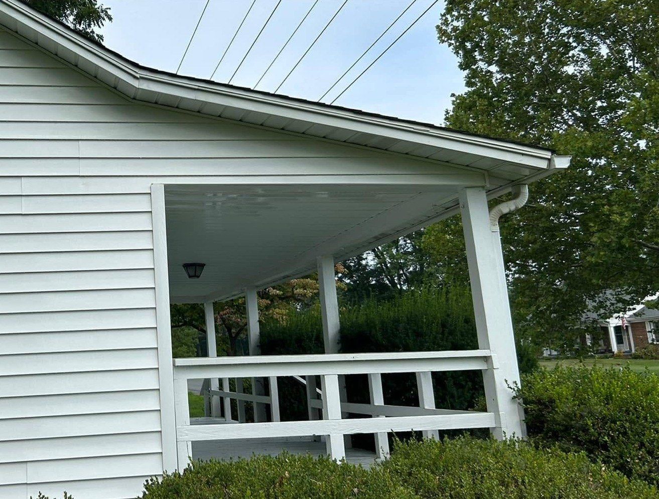 The same siding and porch ceiling after a soft wash, grime gone and siding white