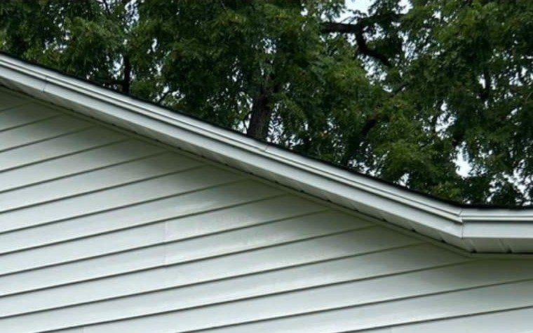 The same gable siding after a soft wash, clean and white under the roof edge