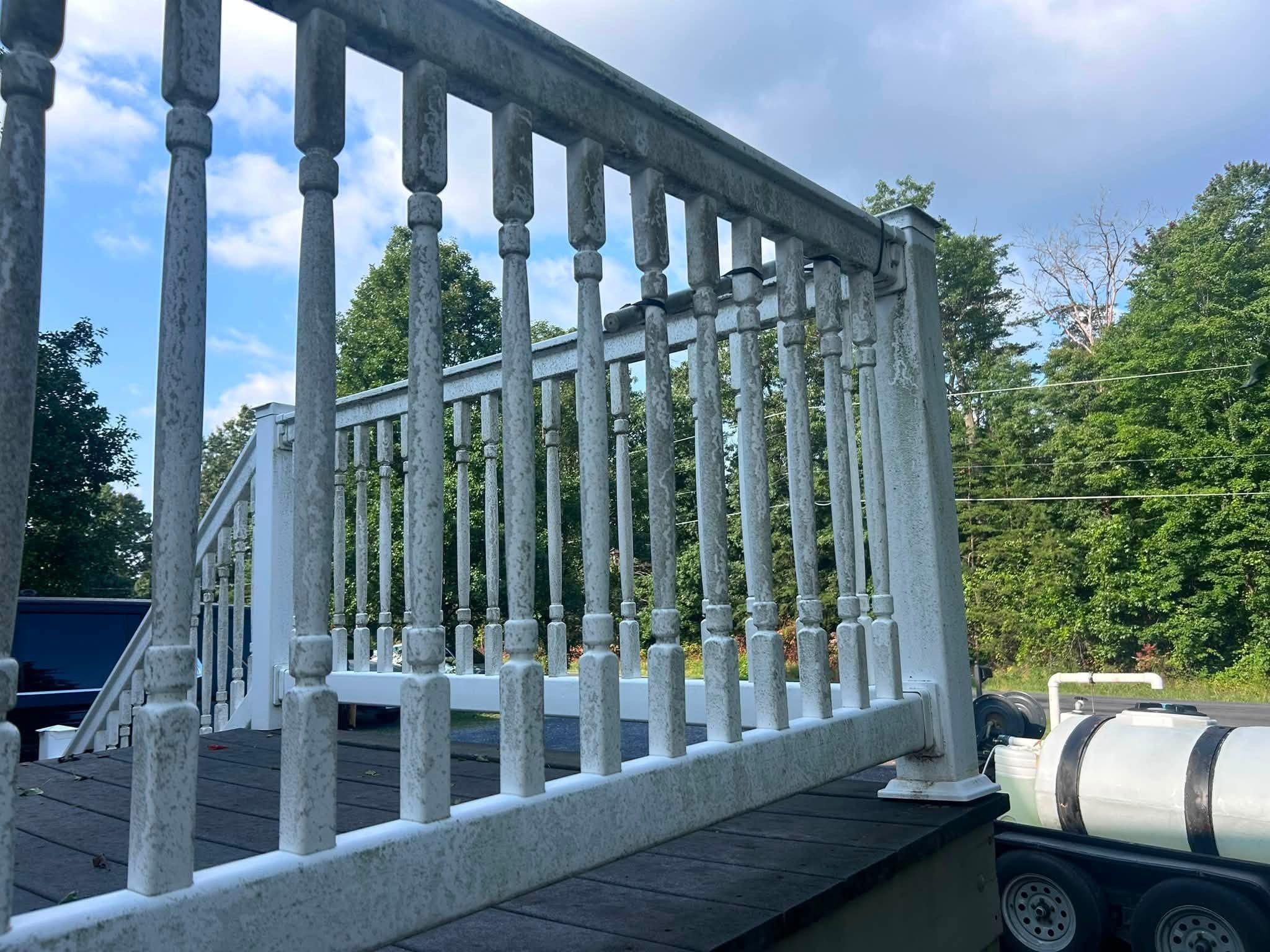 White vinyl deck railing coated in gray-green mildew, a water tank trailer beside the deck