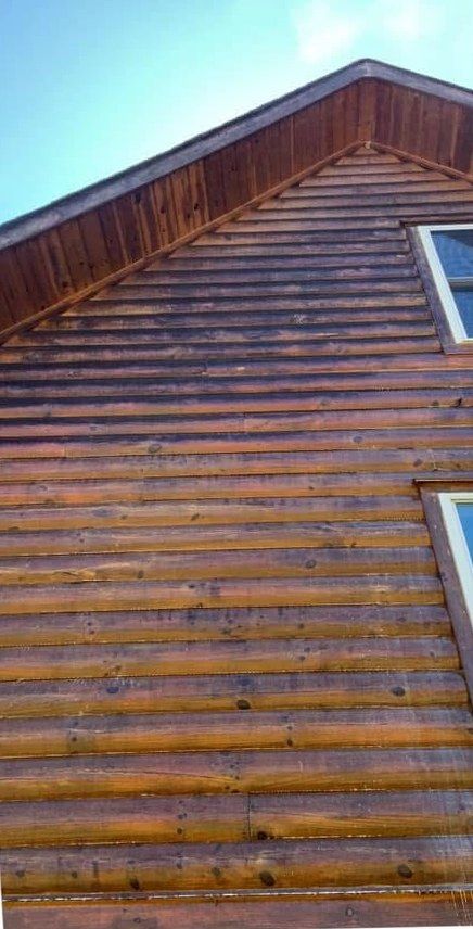 Log siding on a gable darkened by weathering and grime