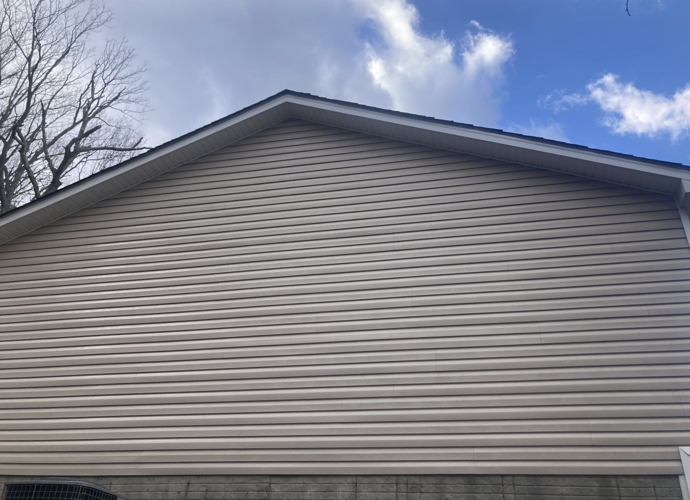 The same gable wall after washing, clean tan siding
